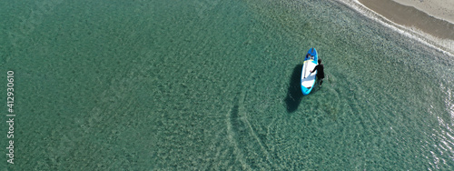 Photography Aerial drone ultra wide photo of fit man on SUP or Stand Up Paddle board in trop