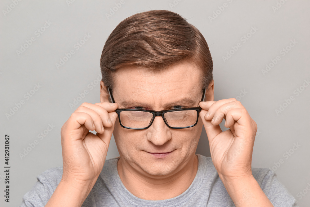 Fototapeta premium Portrait of blond mature man looking attentively over his glasses