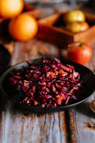 Red cabbage salad (coleslaw) with apples, oranges and walnuts on a dark wooden background, food still life