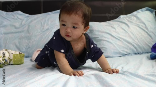 portrait of 8 month Asian Chinese baby boy looks and move around surprisely on a bed photo