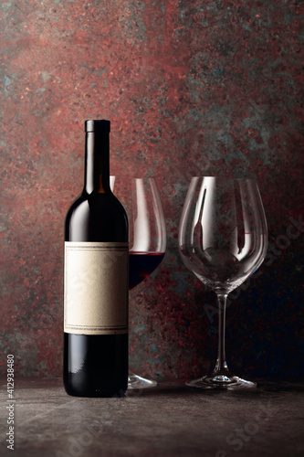 Bottle of red wine with old empty label on rusty brown background.