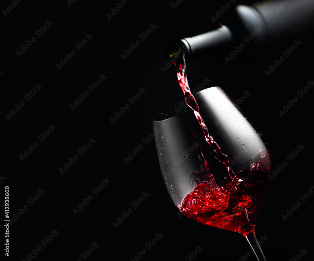 Pouring red wine in a glass goblet. - obrazy, fototapety, plakaty 