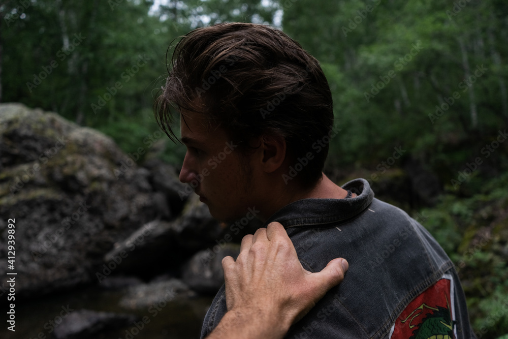 Young man turning around. a hand on a shoulder. guy in the dark forest.