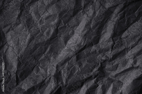 Black crumpled rough paper background. Wrinkled packaging texture. Dark gray grunge background with copy space for design.
