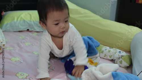 portrait of 8 month Asian Chinese baby boy looks and move around surprisely on a bed photo