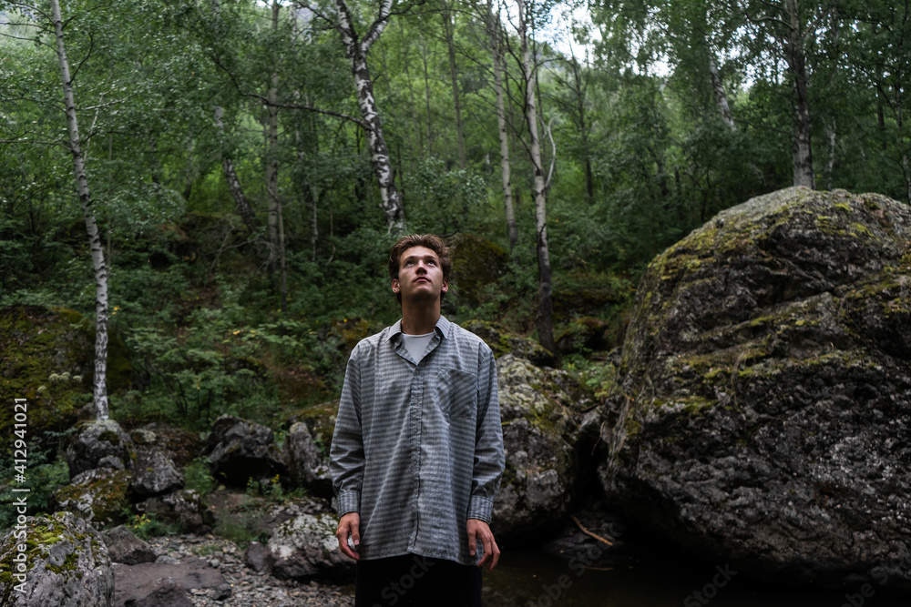 young man stands in the forest. look from the back. outdoor yoga exercises young man stands in the forest. look from the back. outdoor yoga exercises
