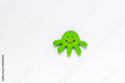Organic baby green octopus isolated on white background with copy space. Baby fun wooden toy and teether on pink background. Top view, flat lay. Wooden animal miniature toys set mockup for babies. © Ramil