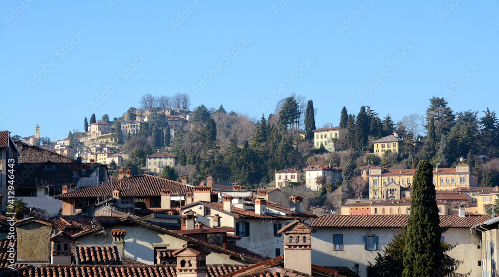 Roofs and chimneys in the residential area of Bergamo Alta with hills and elegant villas in a typical and picturesque scenery of Italy.
