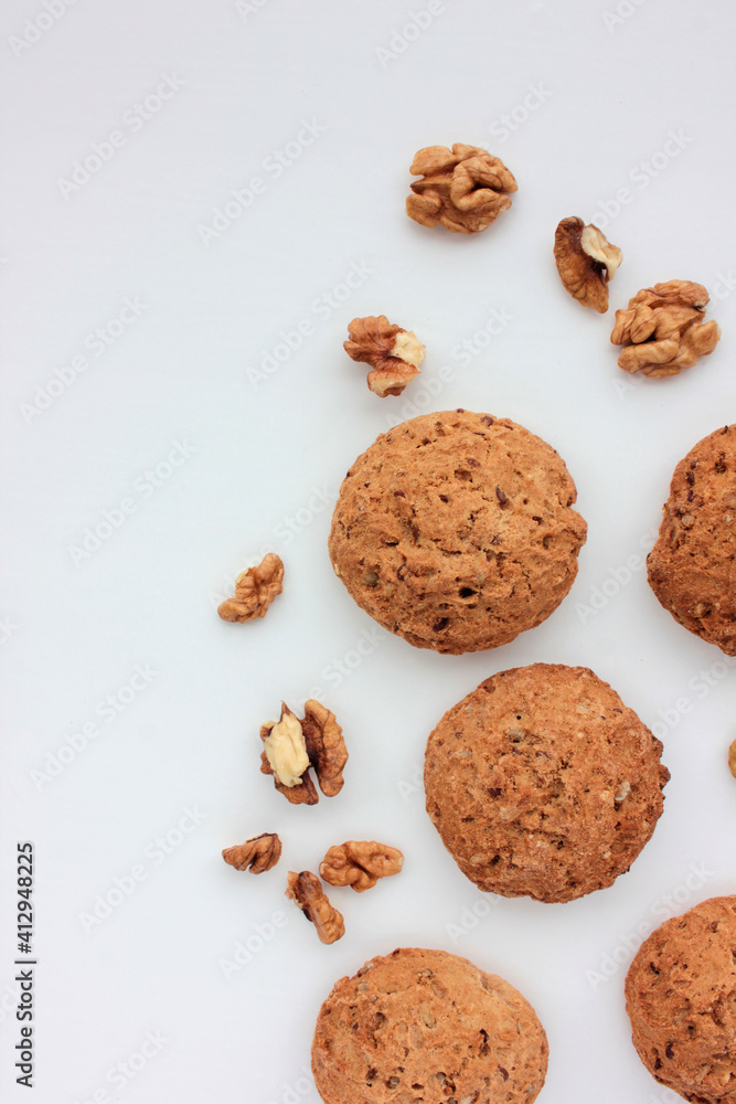 Homemade oatmeal cookies with walnuts on white table. Overhead view of oat biscuits and nuts on white background with copy space Homemade oatmeal cookies with walnuts on white table. Overhead view of oat biscuits and nuts on white background with copy space