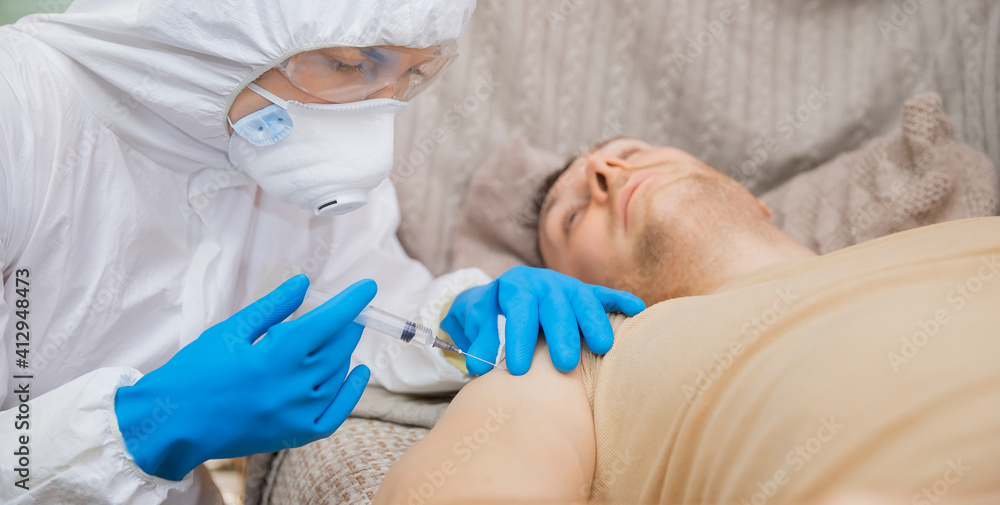 Injecting vaccine nurse in protective suit and blue gloves. Concept vaccination people for coronavirus Covid medicine flu Injecting vaccine nurse in protective suit and blue gloves. Concept vaccination people for coronavirus Covid medicine flu