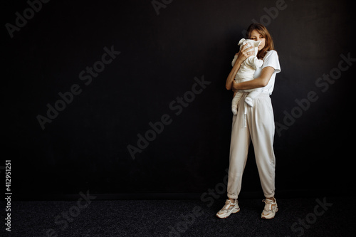 A young caring mother with a child, holding a baby in her arms. Happy woman enjoying motherhood. Photographed in the studio on a black background. © shunevich