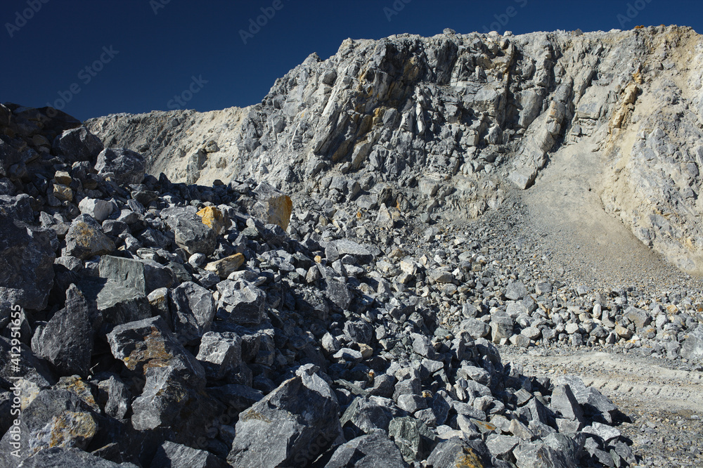 Steep cliffs and stone scree in a quarry against the background of a dark blue sky. Steep cliffs and stone scree in a quarry against the background of a dark blue sky.