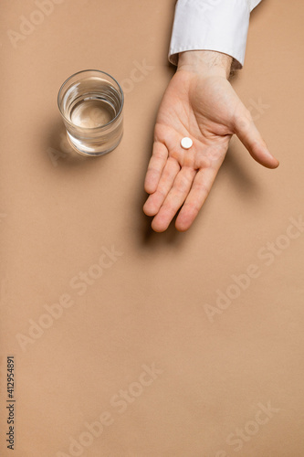 Glass of water and medicine in hand