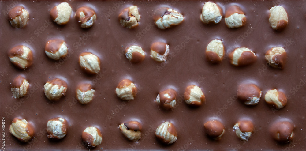 close-up of milk chocolate bar with whole hazelnuts. selective focus. top view close-up of milk chocolate bar with whole hazelnuts. selective focus. top view