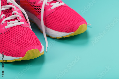 Pink sports sneakers for running on a blue background with free space.