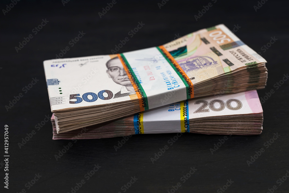 bundles of hryvnia on a black wooden background. Ukrainian money in denominations of 200 and 500 hryvnia.