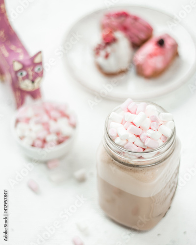 Close-up of a hot drink and mini marshmallows on a white table and in the background Traditional French dessert eclairs