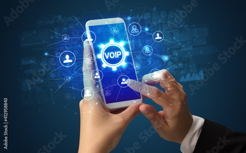 Female hand holding smartphone with VOIP abbreviation, modern technology concept photo