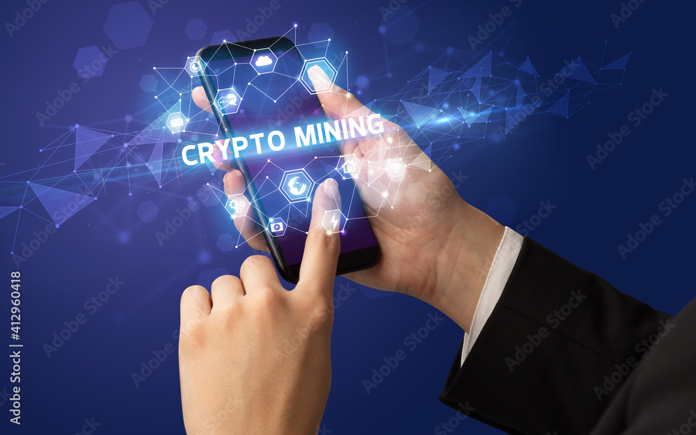 Female hand holding smartphone with CRYPTO MINING inscription, modern technology concept Female hand holding smartphone with CRYPTO MINING inscription, modern technology concept