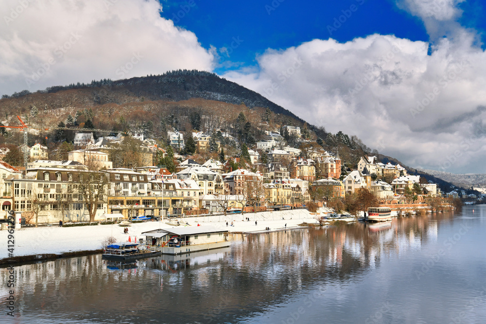 Heidelberg, Germany. View on Odenwald forest hill called Heiligenberg with historical mansions covered in snow and neckar river. View from Theodor Heuss bridge on sunny winter day