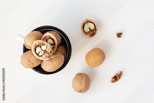 Unshelled and peeled walnuts in a mug and nearby