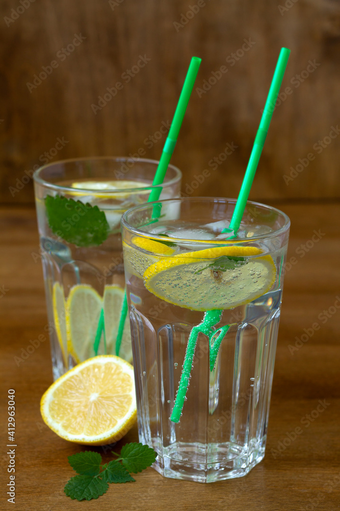 cocktail with lime and mint. Glasses of lemonade with lemon and fresh leafs mint. homemade cold refreshing drink or water with ice on rustic wood background. Copy space. summer drinks. vertical cocktail with lime and mint. Glasses of lemonade with lemon and fresh leafs mint. homemade cold refreshing drink or water with ice on rustic wood background. Copy space. summer drinks. vertical