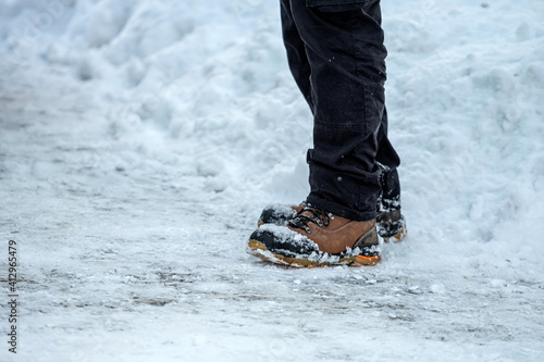 closeup of feet of man with brown leather boots in the snow on side view