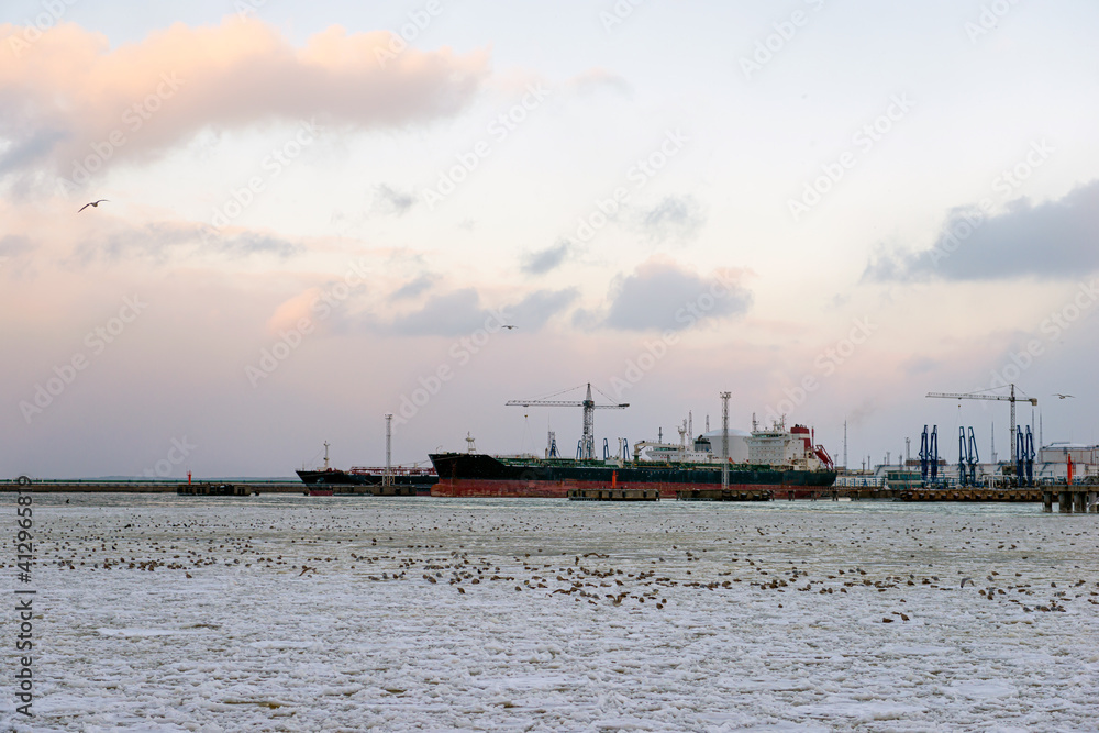 beautiful winter landscape with ship in cargo port fuel terminal at sunset time., Ventspils, Latvia