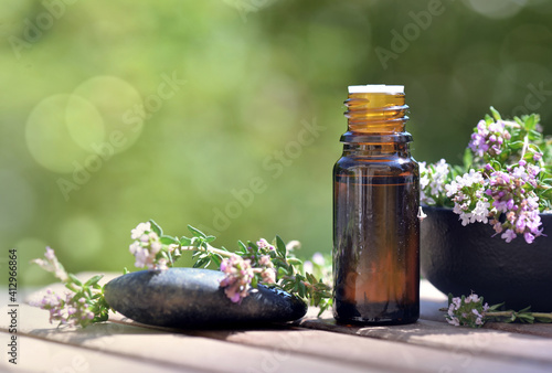  bottle of essential oils spilled on a table with lavender flowers on green bokeh background