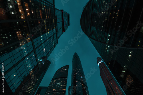 bottom up perspective view of modern city skyscraper buildings with many windows at night. Tall office buildings in Moscow city center
