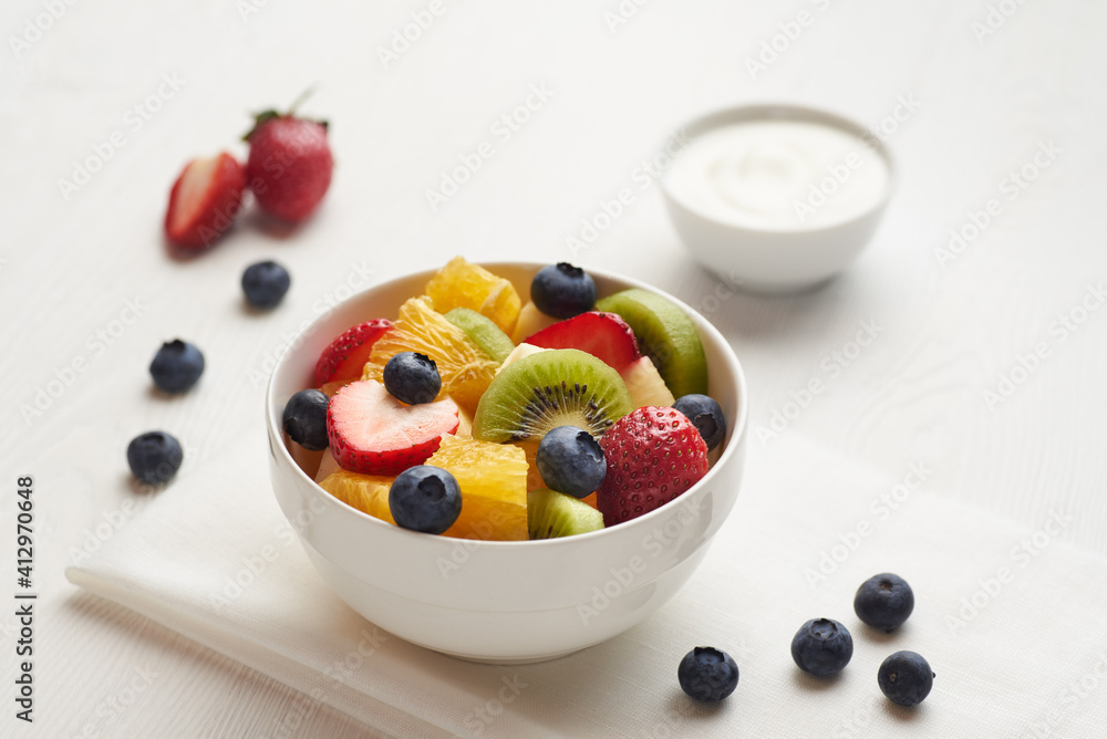 Fruit salad in a white painted wooden table with berry, yoghurt and napkin. Fruit salad in a white painted wooden table with berry, yoghurt and napkin.
