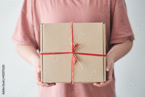 Fototapeta Naklejka Na Ścianę i Meble -  Selected focus. Girl holding a gift box with a red ribbon in her hands