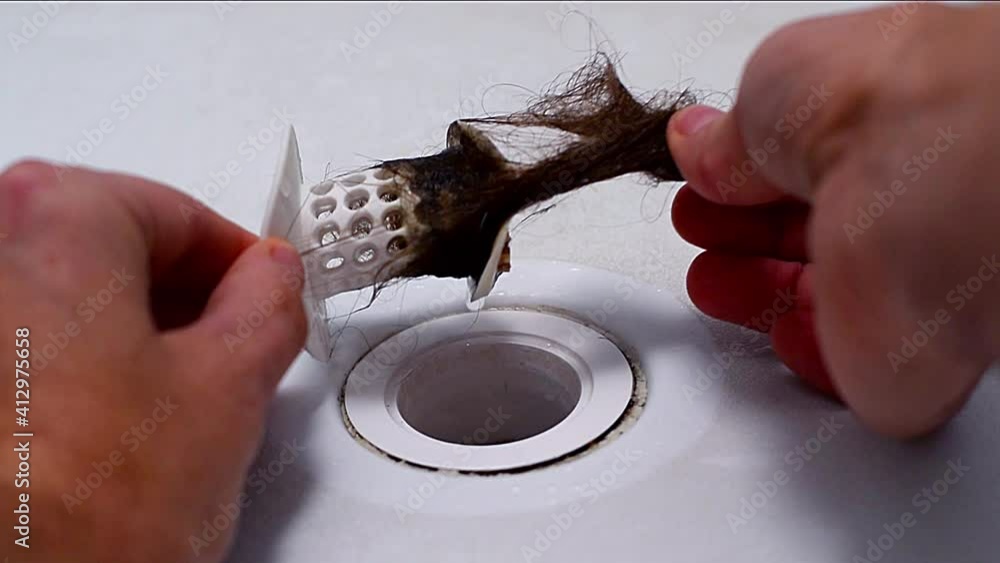 Cleaning hair from drain strainer clogged blocked with long womans hair