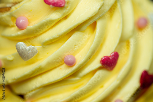 Tasty yellow cream with small sugar hearts. Macro photo of cream.