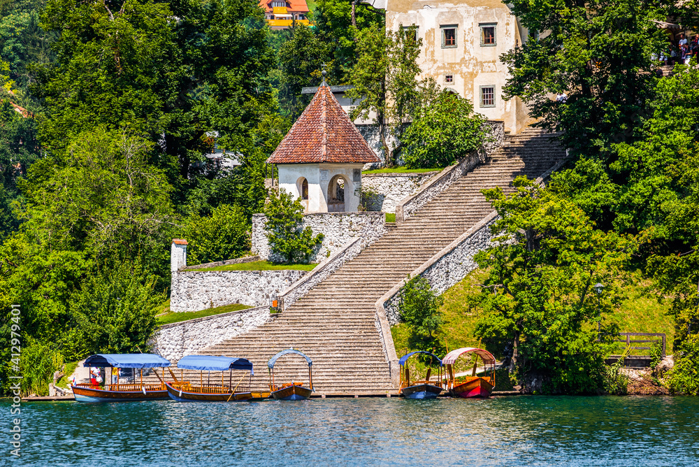 Tourist Attraction. Passenger Boats and Famous Staircase under the Church on Island in the Middle of Bled Lake in Slovenia