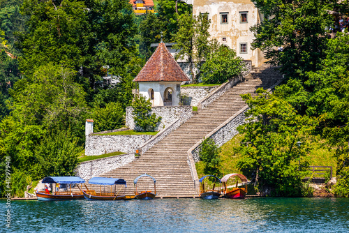 Obraz na płótnie Tourist Attraction. Passenger Boats and Famous Staircase under the Church on Island in the Middle of Bled Lake in Slovenia w salonie