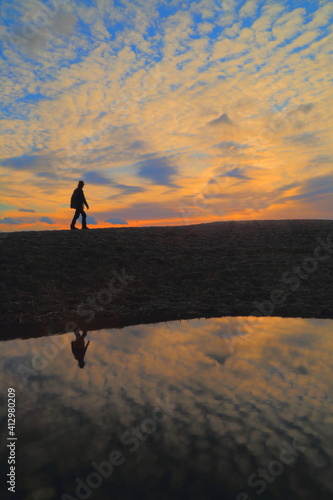 Silhouette of man walking on beach at the sunset