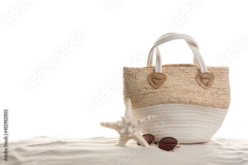 Stylish bag, sunglasses and starfish on sand against white background. Beach accessories