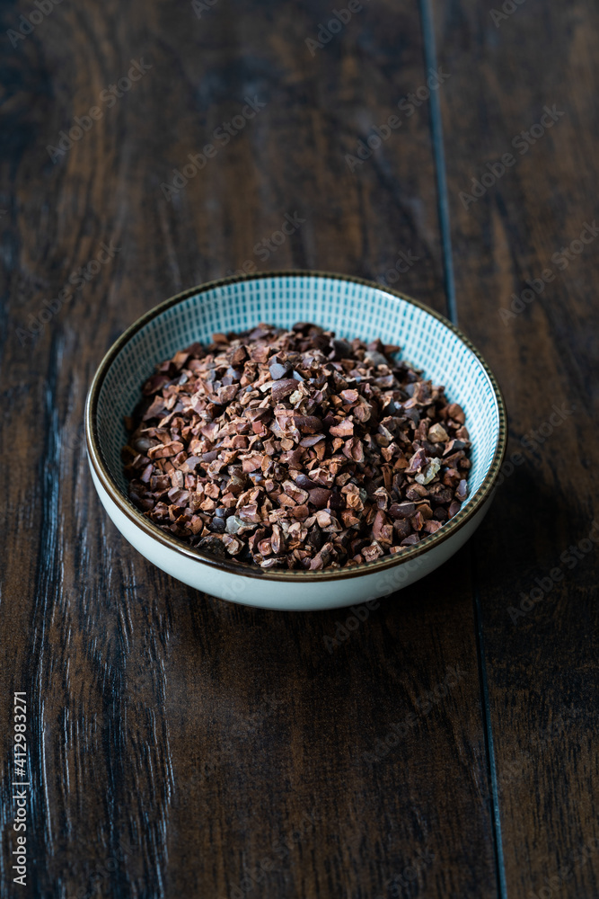 Chocolate Cacao Nibs or Cocoa Nibs in Bowl Ready to Use on Dark Wooden Surface. Chocolate Cacao Nibs or Cocoa Nibs in Bowl Ready to Use on Dark Wooden Surface.