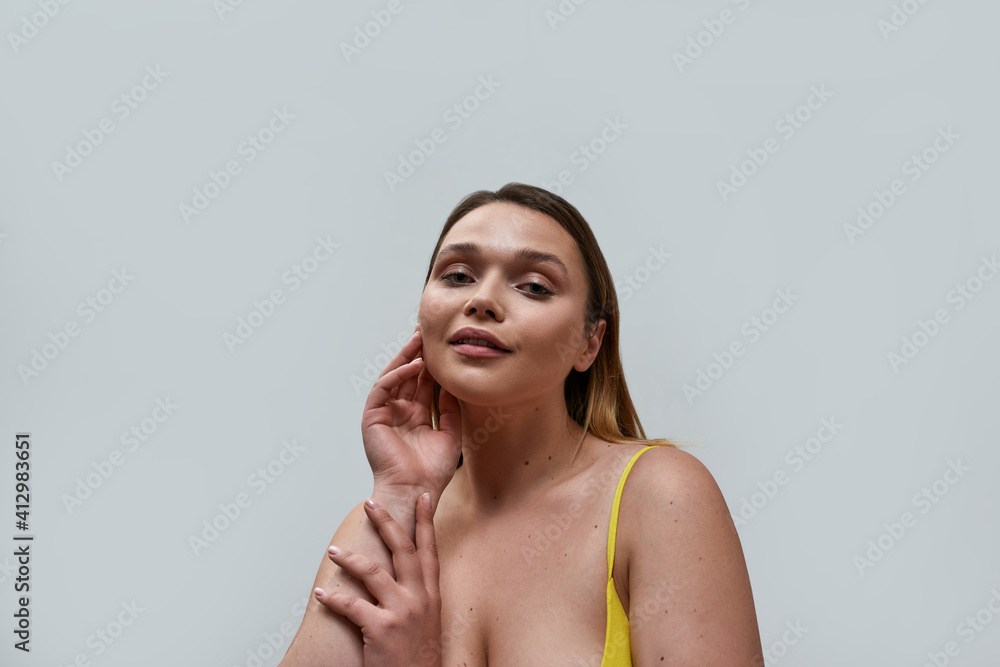 Portrait of sensual curvy young woman wearing yellow bra posing isolated over grey background Portrait of sensual curvy young woman wearing yellow bra posing isolated over grey background