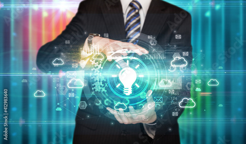 Businessman holding light bulb icon in his hands with multiple technology symbols around it