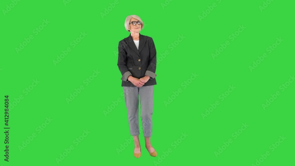 Charming elder woman in fashionable glasses standing and waiting on a Green Screen, Chroma Key. Charming elder woman in fashionable glasses standing and waiting on a Green Screen, Chroma Key.