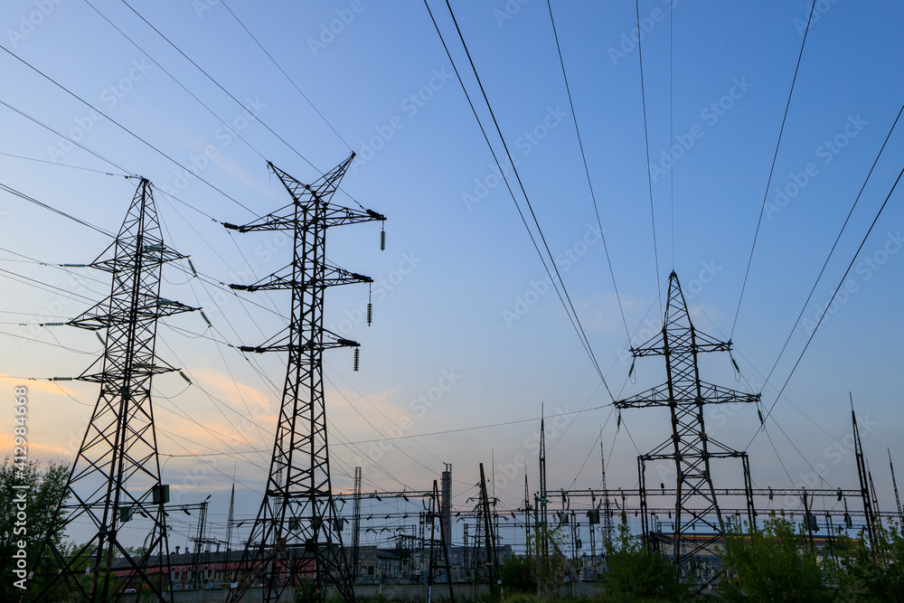 against the background of the evening sky, a large number of power lines with metal supports