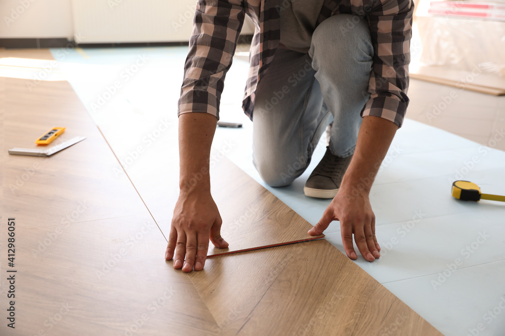 Worker installing laminated wooden floor indoors, closeup - obrazy, fototapety, plakaty 