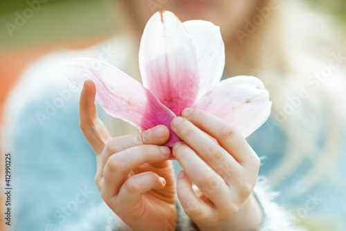 Closeup on magnolia petals in child hand in summer
