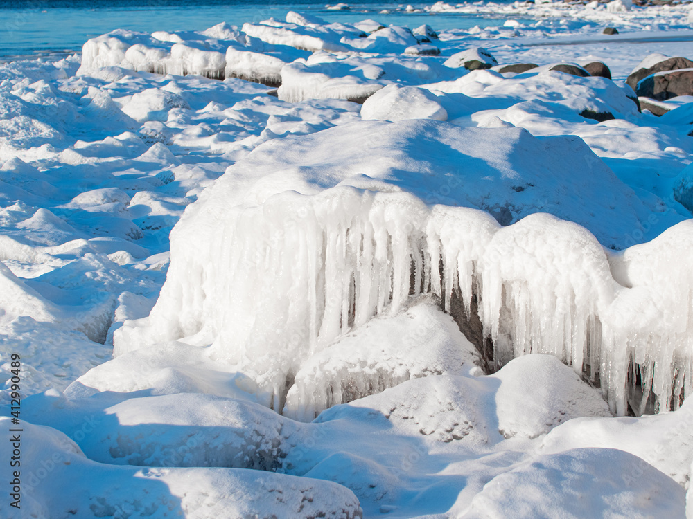 Obraz premium In the winter, stones are icy on the sea shore. Icicles hung from large pieces of ice