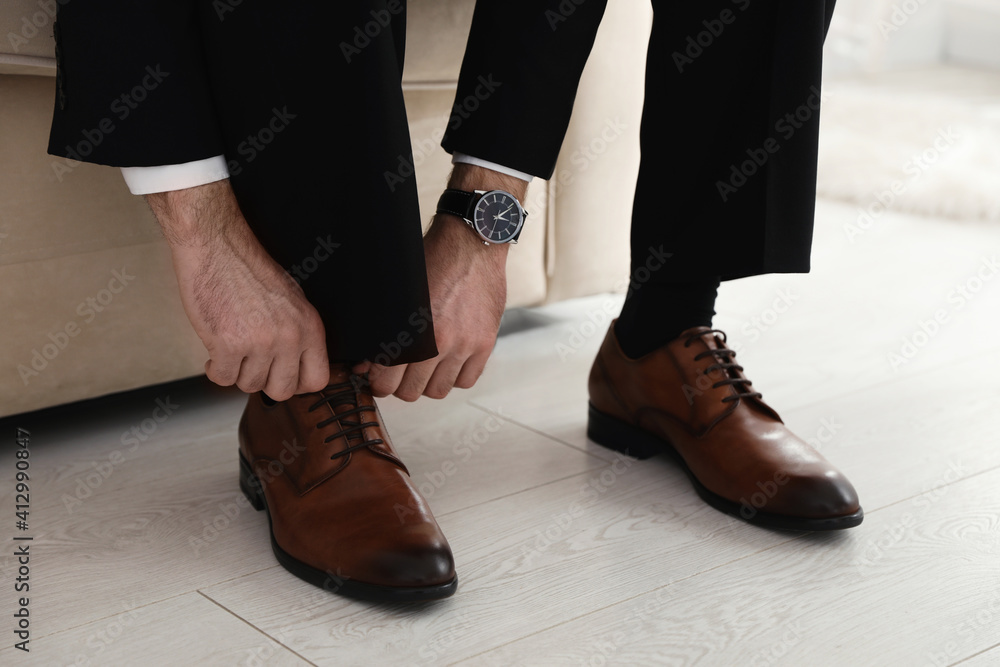Groom putting on elegant wedding shoes indoors, closeup Groom putting on elegant wedding shoes indoors, closeup