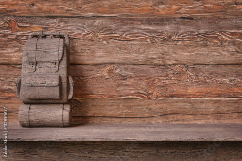 Sculpted wood backpack on a shelf with copy space and rustic wood background. Concept of exhibition of products related to adventure sports. 3d render illustration.