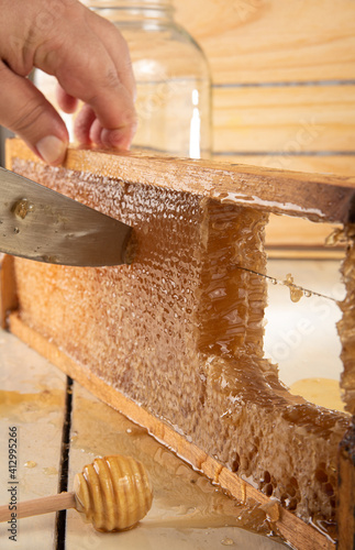Honeycomb, cutting honeycombs from the medeira with a knife. Wooden background, selective focus. photo