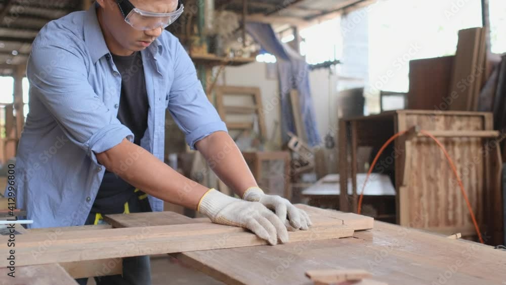Asian carpenter man or craftsman with protection cut the wood timber by using saw machine in workplace area. Asian carpenter man or craftsman with protection cut the wood timber by using saw machine in workplace area.